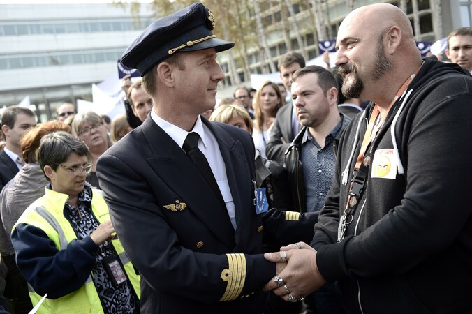 Een werknemer en piloot van Air France schudden elkaar de hand tijdens een staking die gisteren plaatsvond.