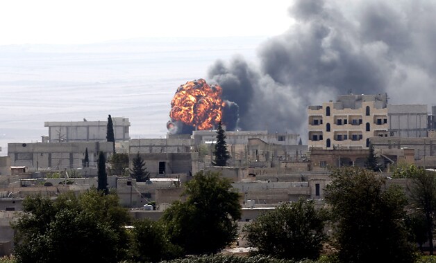 Grote rookpluimen rijzen op uit gebouwen in de Syrische stad Kobane.