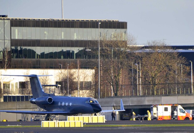 Hulpverleners met beschermende pakken begeleiden een ebolapatient vanuit een Gulfstream III van Phoenix Air naar een ambulance. Het gaat om een militair van de Verenigde Naties Vredesmacht in Liberia (UNMIL) die verder in het Calamiteitenhospitaal van het UMC behandeld zal worden.