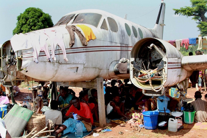 Vluchtelingen schuilen onder een vliegtuigwrak op de luchthaven van Bangui.