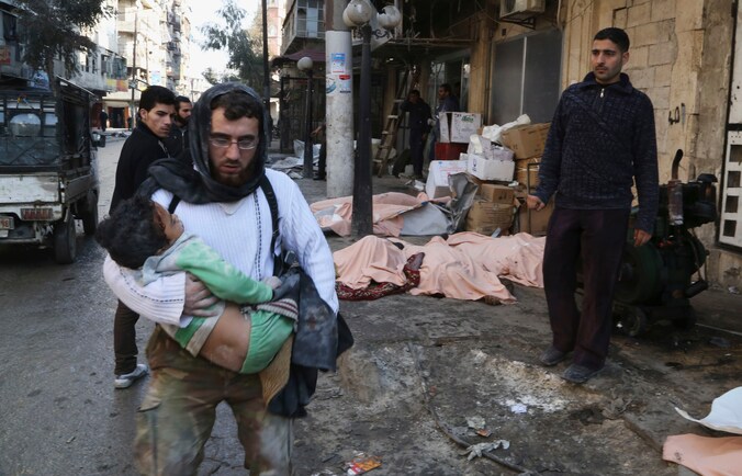 Een man draagt een gewond kind dat net onder het puin vandaan is gehaald na een bombardement in Aleppo.