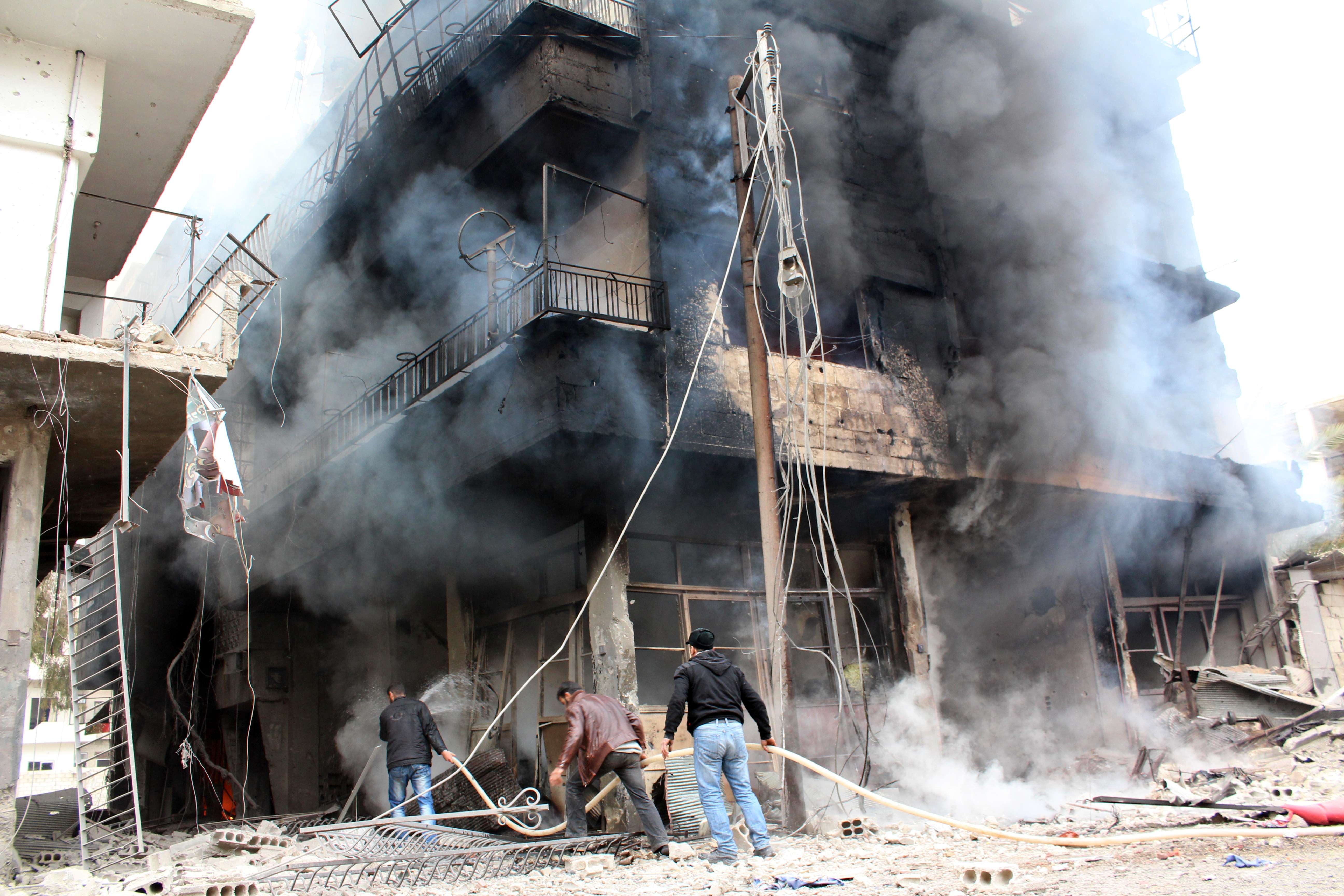 Mannen proberen een brand in een gebouw in Damascus te blussen.