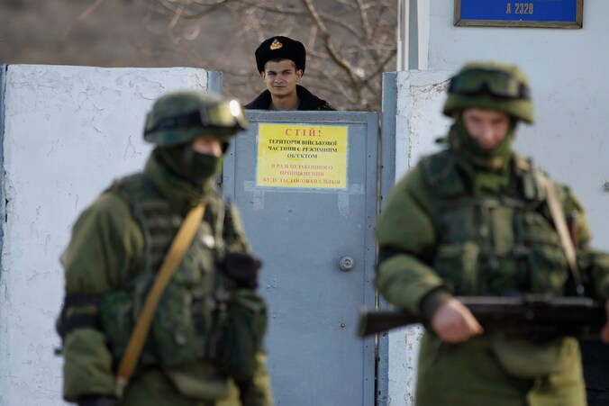 Een Oekraïens militair kijkt vanuit zijn kazerne naar Russische troepen nabij de stad Simferopol op de Krim.