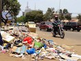 Een motorrijder passeert een berg afval in de hoofdstad Conakry.