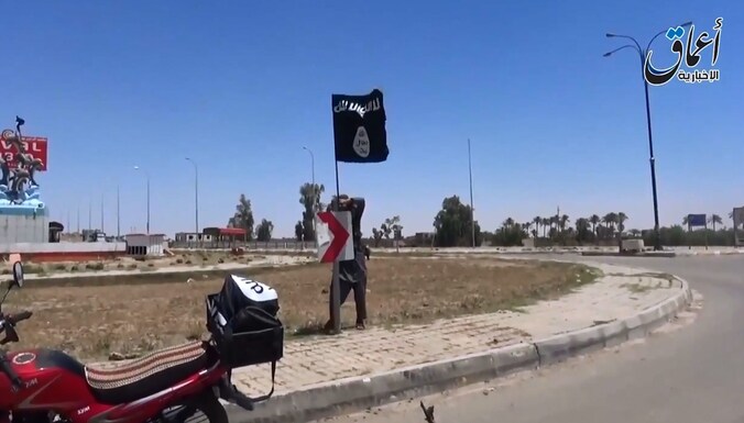 Een IS-strijder plaatst een vlag van de terreurbeweging in de stad Ramadi.