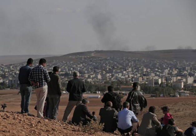 Op een heuvel bij de Turks-Syrische grens zijn de gevechten in Kobani te zien.