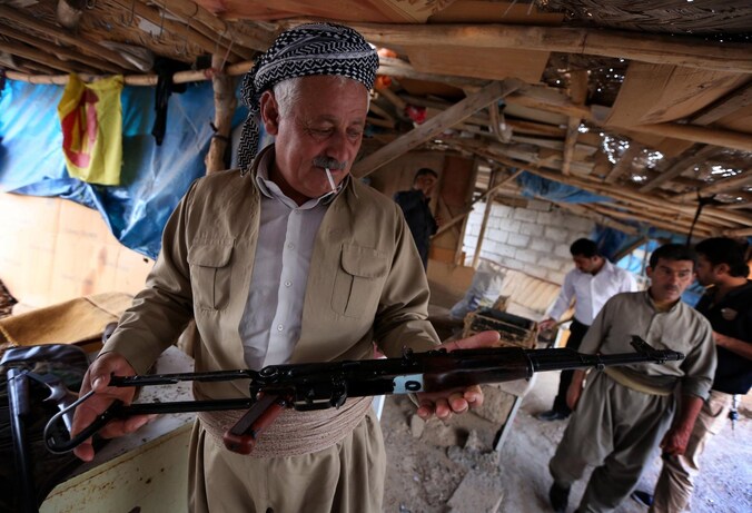 Een Koerdische man inspecteert de koopwaar op een wapenmarkt in Irak.