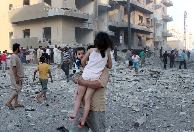 Een man draagt zijn twee kinderen weg van de plek van een explosie in de Syrische stad Raqqa.