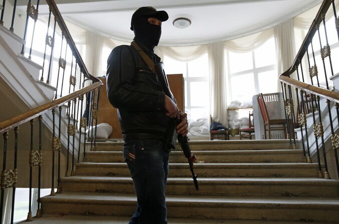 Een pro-Russische betoger houdt de wacht in het veroverde regeringsgebouw in Lugansk.