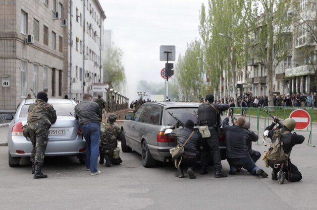 Gewapende pro-Russische separatisten zoeken dekking achter auto's in de Oost-Oekraïense stad Loehansk.