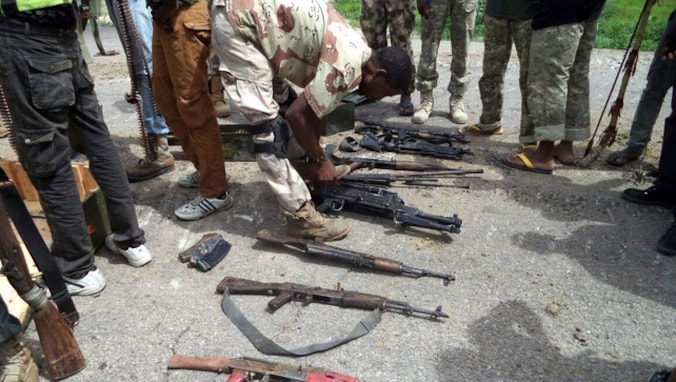 Een soldaat van het Nigeriaanse leger neemt wapens van Boko Haram-strijders in beslag.
