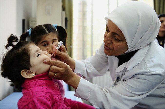 Een werknemer van UNICEF dient een Syrisch kind in de hoofdstad Damascus een vaccinatie toe tegen polio.