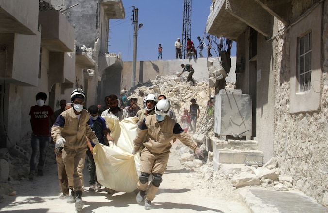 Reddingswerkers dragen het lichaam weg van een slachtoffer van een vermoedelijke luchtaanval van het Syrisch leger, gisteren in Aleppo.