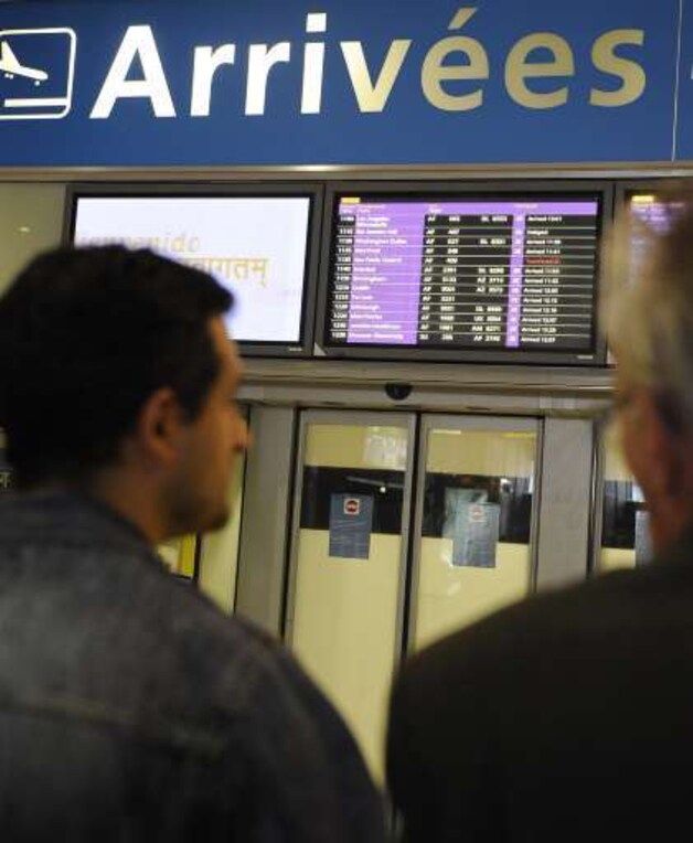 Familieleden van de passagiers staren verweesd voor zich uit in de aankomsthal in Parijs.
