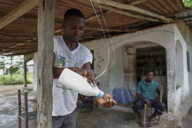 Een man wast zijn handen aan een winkel in Liberia.