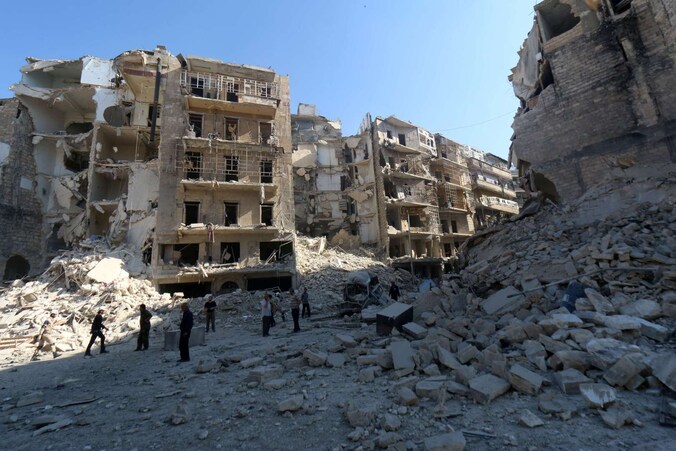 Inwoners van de Al-Chaar-wijk staan te midden van hun vernielde huizen in Aleppo, 30 mei.