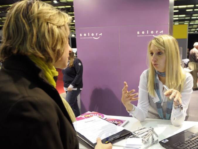 Een vrouw gaat inlichten inwinnen bij de stand van Selor, het selectiebureau voor federale ambtenaren.