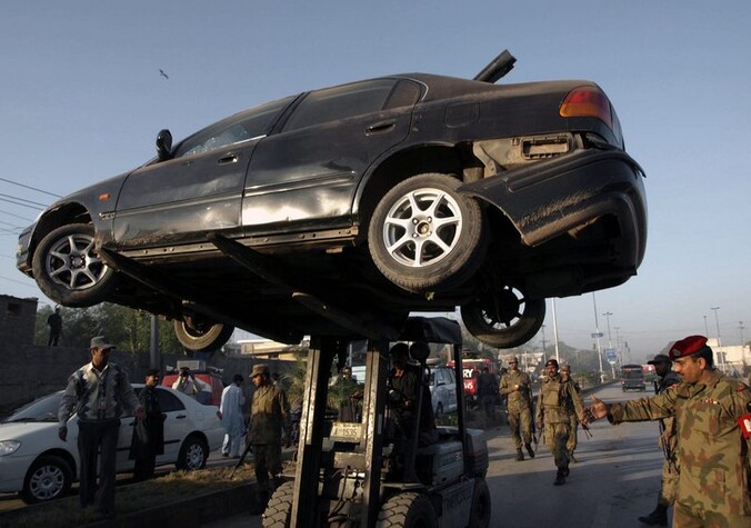 Een auto die beschadigd raakte bij een bomaanslag op het regionaal hoofdkwartier van de Pakistaanse geheime dienst ISI wordt weggetakeld in Peshawar.