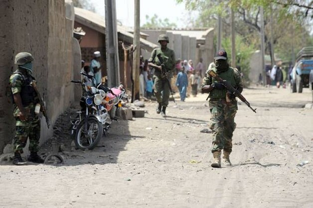 Nigeriaanse soldaten lopen door Baga.