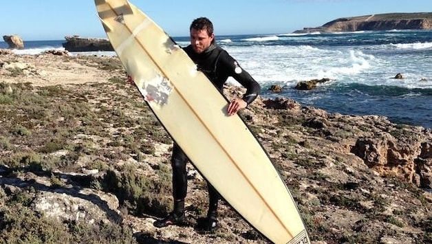 Andrew McLeod met het surfboard waar de haai zijn tanden in zette.