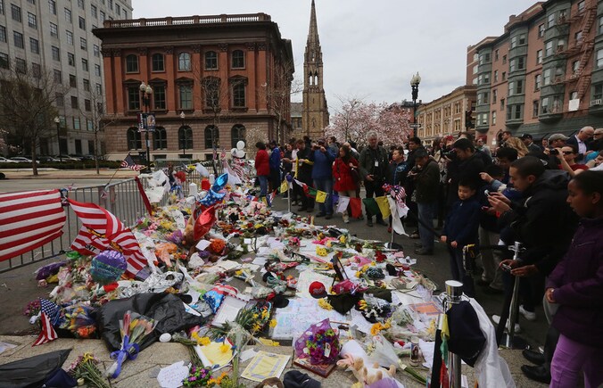 Mensen leggen bloemen en kaarten neer bij een herdenkingsplek in Boston.