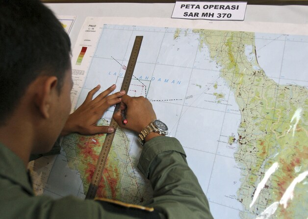 Een Indonesische luchtmachtofficier tekent een gebied op de kaart waar is gezocht naar de vermiste Boeing 777.
