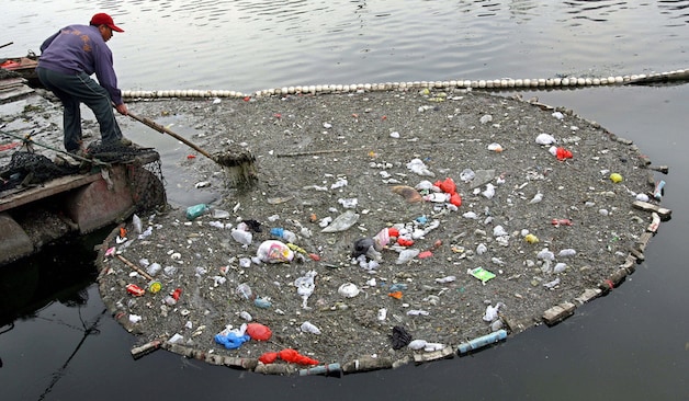 Een werker haalt afval uit een rivier bij Peking.