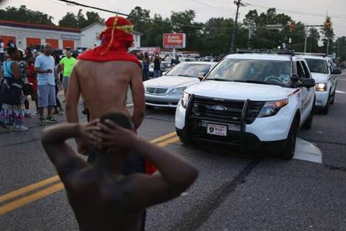 Demonstranten staan voor politieauto's in Ferguson