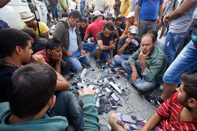 Migranten laden hun gsm op in Boedapest.