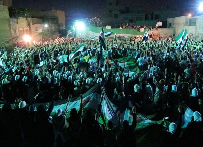 Syrische opposanten zwaaien met hun revolutionaire vlag tijdens een manifestatie