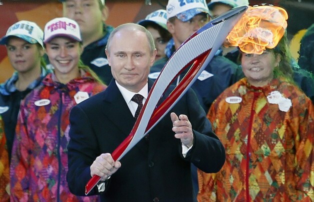 De Russische president Vladimir Poetin poseerde gisteren met de Olympische vlam op het Rode Plein in Moskou.