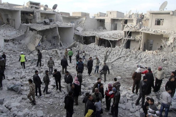 Mensen lopen tussen de brokstukken van vanuit de lucht gebombardeerde huizenblokken in Aleppo.
