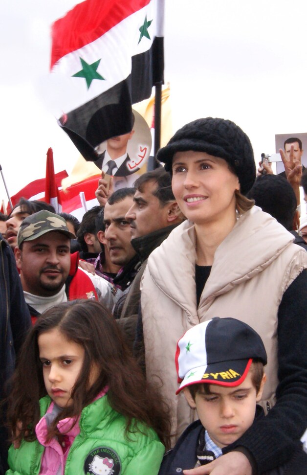 Asma al-Assad luistert met haar kinderen naar een speech van haar man. Ze kwam zelf niet aan het woord.