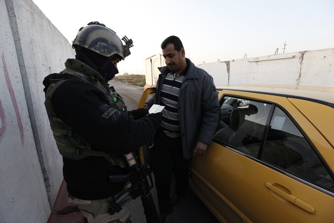 Een Iraakse soldaat controleert de identiteit van een automobilist nabij Bagdad. In het hele land zijn verscherpte controles in verband met de toegenomen gewelddadigheden.