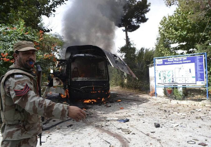 Een soldaat bij de brandende bus in Quetta.