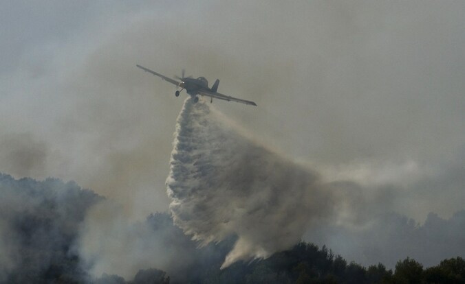 Een blusvliegtuig boven de brandende bossen van Mallorca.