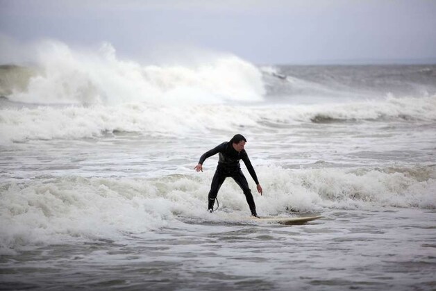 Een surfer profiteert van de hoge golven.