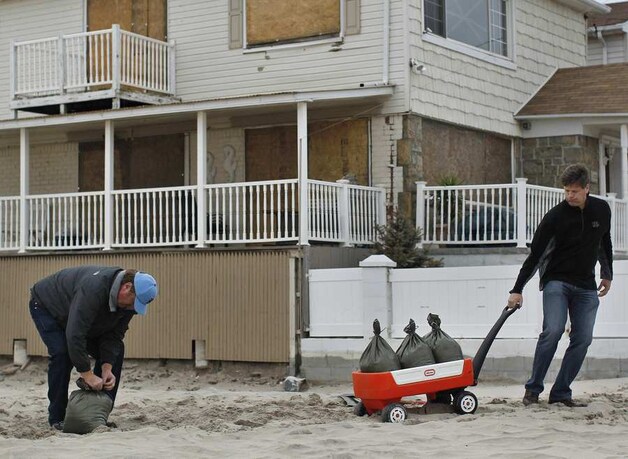 Inwoners van Queens vullen zandzakjes op Rockaway beach.