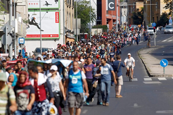 Migranten wandelen in een van de hoofdstraten van Boedapest.