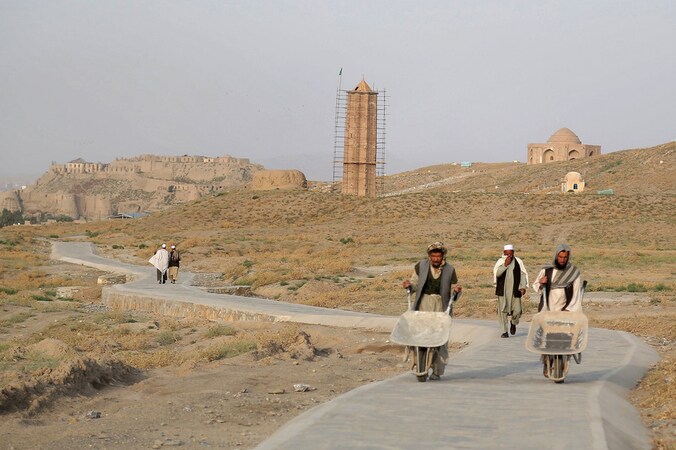 Arbeiders wandelen langs een eeuwenoude minaret in Ghazni.