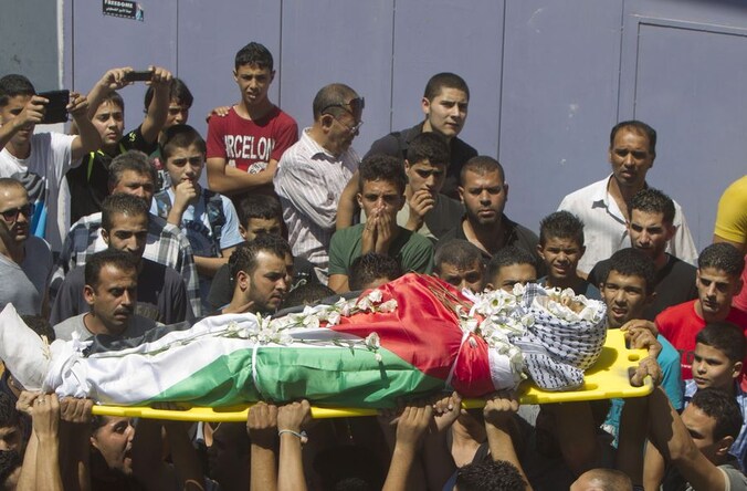 Een van de lijken wordt weggedragen.