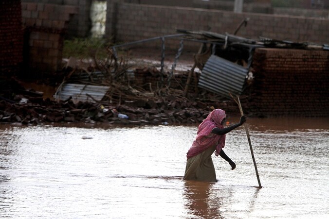 Een vrouw waadt door het water in Khartoem.