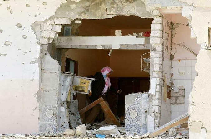 Een vrouw inspecteert een gehavend huis in Zawiyah, 48 km ten westen van Tripoli.