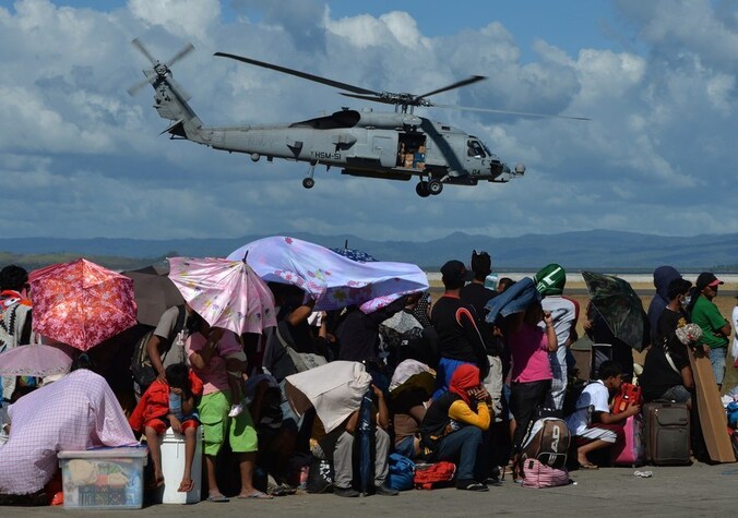 Slachtoffers van de tyfoon Haiyan wachten op het vliegveld van Tacloban op een vlucht om de zwaar beschadigde stad te ontvluchten.