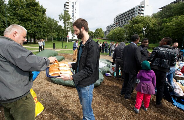 Een vrijwilliger deelt broodjes uit in het Brusselse Maximiliaanpark.