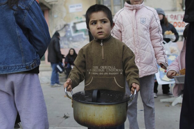 Kinderen en daklozen bij een voedselbedeling door een humanitaire organisatie in Athene.