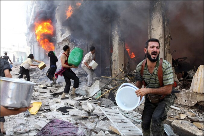 Burgers proberen het vuur te blussen nadat het Syrische leger een appartementsblok bombardeerde.