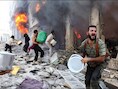 Burgers proberen het vuur te blussen nadat het Syrische leger een appartementsblok bombardeerde.