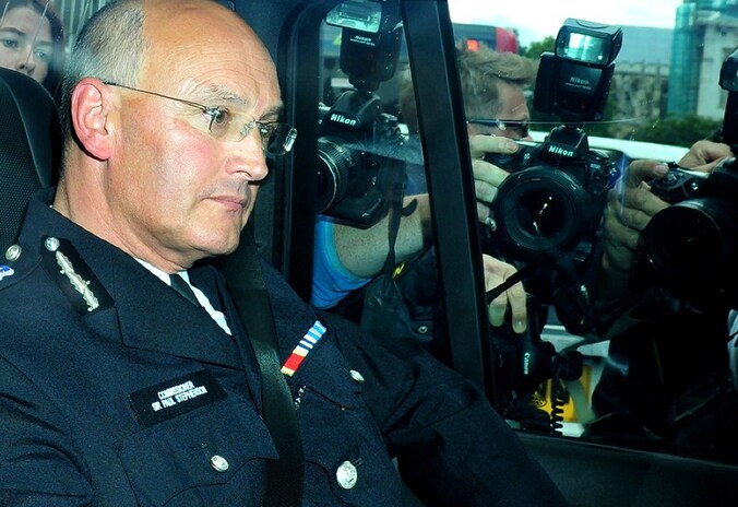 Paul Stephenson verlaat na de zitting het Britse parlement. Persfotografen belegeren de wagen.