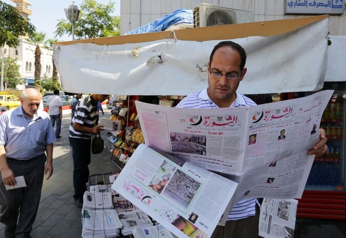 Een man leest een krant in Damascus vandaag.